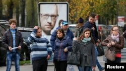 Ukrajinci u Kijevu stoje ispred bilborda sa likom ukrajinskog premijera Arsenija Jacenjuka, 21. oktobra 2014. 