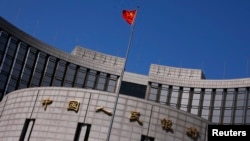 FILE - A Chinese national flag flutters outside the headquarters of the People's Bank of China, the Chinese central bank, in Beijing.