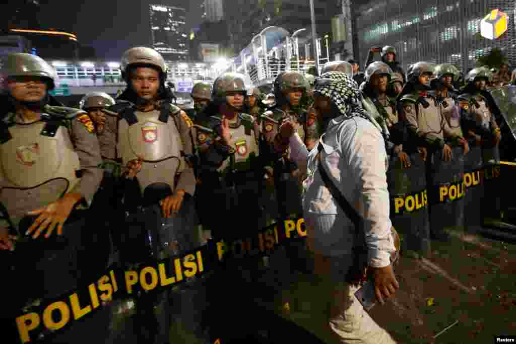 Seorang peserta unjuk rasa bersalaman dengan polisi anti huru-hara menyusul pengumuman rekapitulasi hasil pilpres, di luar kantor Bawaslu di Jakarta, 21 Mei 2019. (Foto: Reuters/Willy Kurniawan)