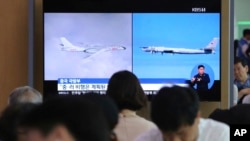 People watch a TV showing images of Russian Tu-95 bomber and Chinese H-6 bomber, left, during a news program at the Seoul Railway Station in Seoul, South Korea, July 24, 2019.