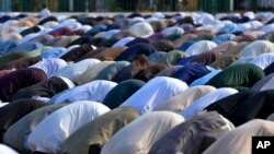 FILE—A Muslim child stands beside his father performing an Eid al-Fitr prayer with others, marking the end of the fasting month of Ramadan, in Rawalpindi, Pakistan, April, 10, 2024.