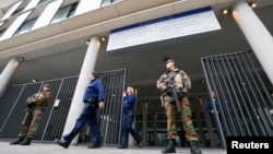 Armed soldiers stand guard outside the courthouse where suspects are expected to be questioned in the fatal shootings in Paris on Friday, in Brussels, Belgium, November 16, 2015.