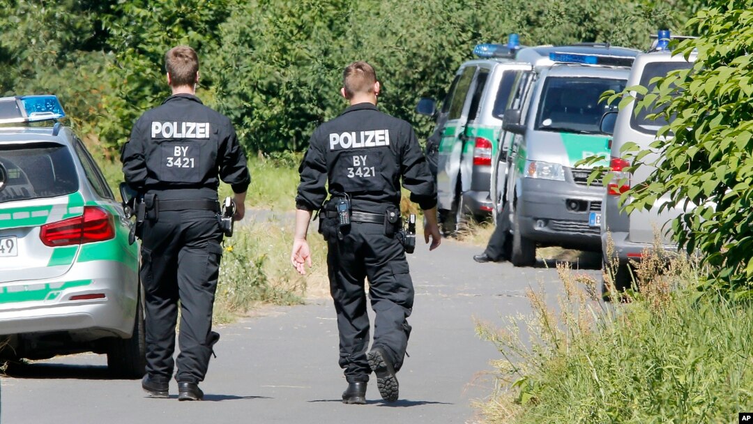 Police officers walk to the crime scene near the river Main, background, where a 17-year-old man from Afghanistan was shot the night before, near Wuerzburg, Germany, Tuesday, July 19, 2016.