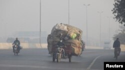 FILE - A man rides a motor tricycle, loaded with sacks of recyclables, amid dense smog in Lahore, Pakistan November 24, 2021. (REUTERS/Mohsin Raza/File Photo)