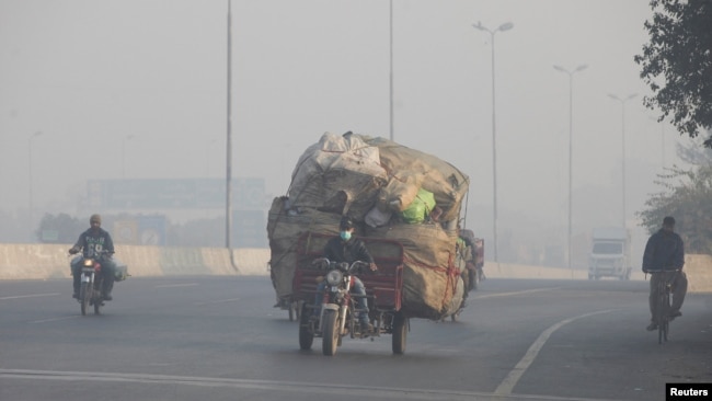 FILE - A man rides a motor tricycle, loaded with sacks of recyclables, amid dense smog in Lahore, Pakistan November 24, 2021. (REUTERS/Mohsin Raza/File Photo)