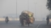 FILE PHOTO: Man rides a motor tricycle, loaded with sacks of recyclables, amid dense smog in Lahore