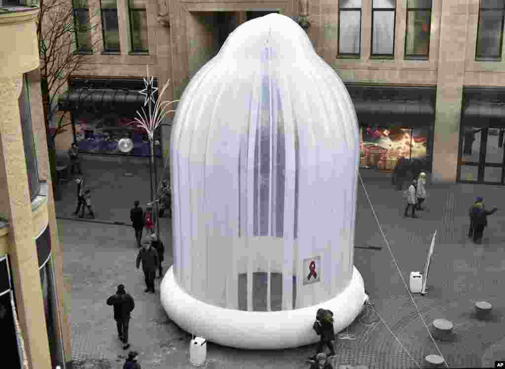 People pass a giant condom on a pedestrian street in Cologne, Germany, to promote safer sex prior the World AIDS Day on Dec. 1.