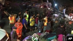 Kerumunan orang menyaksikan bus yang hancur akibat kecelakaan di provinsi Nakhon Ratchasima, Thailand, Rabu malam, 21 Maret 2018. Bus wisata carter kehilangan kontrol pada saat melewati tikungan tajam dan menurun di timur laut Thailand dan meluncur ke pinggir jalan. (Berita Harian melalui AP)