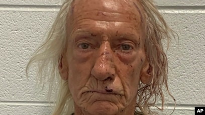a man with long hair and a white shirt is looking at the camera