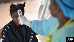 FILE - A girl suspected of being infected with the Ebola virus has her temperature checked at a hospital in Kenema, Guinea, Aug. 16, 2014. Four people have died of Ebola in Guinea, the first resurgence of the fever there since a 2013-16 epidemic.