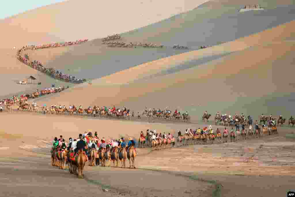 Tourists ride camels in the desert in Dunhuang in China&#39;s northwestern Gansu province.