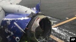 The engine on a Southwest Airlines plane is inspected as it sits on the runway at the Philadelphia International Airport after it made an emergency landing in Philadelphia, April 17, 2018. (Amanda Bourman via AP)