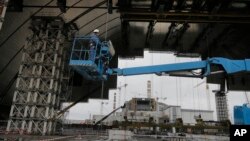 Construction workers assist in the assembly of a gigantic steel arch to cover the remnants of the exploded reactor at the Chernobyl nuclear power plant in Chernobyl, Ukraine, March 23, 2016.