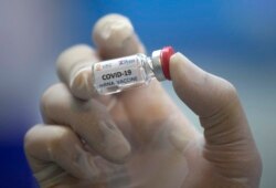 FILE - A lab technician holds a bottle containing results for a COVID-19 vaccine at a testing center run by Chulalongkorn University in Saraburi Province, north of Bangkok, Thailand, May 23, 2020.