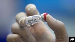 FILE - A lab technician holds a bottle containing results for a COVID-19 vaccine at a testing center run by Chulalongkorn University in Saraburi Province, north of Bangkok, Thailand, May 23, 2020.