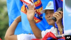 Supporters of the ruling Cambodian People's Party wave from a vehicle during a commune elections campaign rally in Phnom Penh, Friday, May 18, 2012.