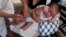 A mother holds her baby as he receives a pneumococcal vaccination during a national vaccination campaign in Managua, April 15, 2013.