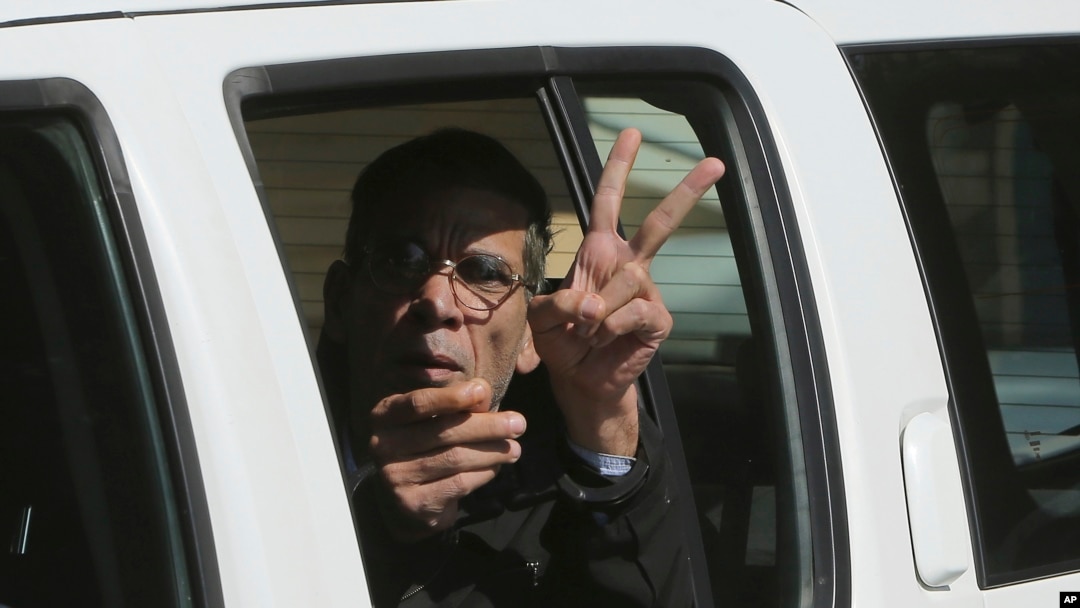 EgyptAir plane hijacking suspect Seif Eddin Mustafa flashes the victory sign as he leaves a court in a police car after a remand hearing as authorities investigate him on charges including hijacking, illegal possession of explosives and abduction in the Cypriot coastal town of Larnaca Wednesday, March 30, 2016. 