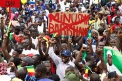 A man holds a banner against the United Nations Multidimensional Integrated Stabilization Misiion in Mali (MINUSMA) and Barkhane, an anti-insurgent operation, during a protest to support the Malian army in Bamako, Mali, on Aug. 21, 2020.