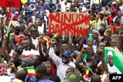 A man holds a banner against the United Nations Multidimensional Integrated Stabilization Misiion in Mali (MINUSMA) and Barkhane, an anti-insurgent operation, during a protest to support the Malian army in Bamako, Mali, on Aug. 21, 2020.