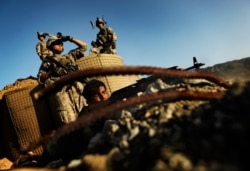 FILE - A sergeant from the Afghan National Army, joined by US soldiers, trains his AK-47 on a shooting range in Zerok District, East Paktika province in Afghanistan, Saturday, Sept. 19, 2009.