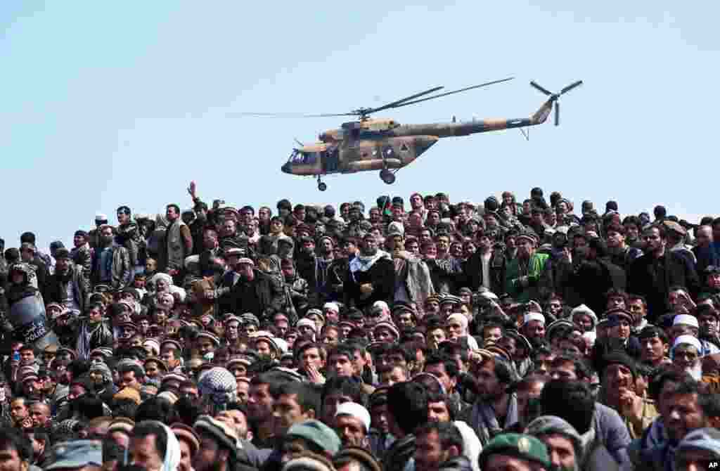 An Afghan National Army (ANA) helicopter flies as Afghan men attend the burial of country&#39;s influential Vice President Mohammad Qasim Fahim during his funeral procession in Kabul.