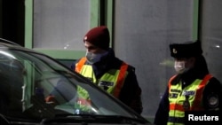 Hungarian police officers wearing protective face masks check driver's documents who crosses the Hungary-Austria border using a one-time special passage in Hegyeshalom, Hungary, March 17, 2020.