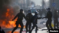 German riot police officers clash with a protestor (3L) outside the new European Central Bank (ECB) headquarters during riots in Frankfurt, March 18, 2015.