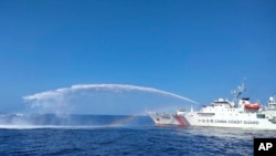 Sebuah kapal Penjaga Pantai China, di sebelah kanan, menggunakan meriam airnya terhadap kapal Biro Perikanan dan Sumber Daya Perairan Filipina (BFAR), saat mendekati Scarborough Shoal di Laut China Selatan yang disengketakan, pada 9 Desember 2023. (Foto: via AP)