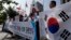 South Korean protesters shout slogans as they hold national flags during a press conference against abrupt cancellation by North Korea of planned reunions for families separated by the Korean War, Sept. 23, 2013.