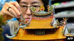 En esta imagen tomada el 5 de agosto de 2020, el artista de modelos en miniatura Chen Shih-jen posa para una fotografía con su trabajo durante una entrevista en FM Dioramas en Taoyuan, norte de Taiwán.