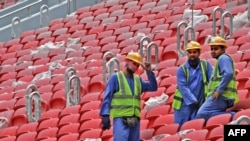 Para pekerja konstruksi berdiri di bangku penonton stadion al-Bayt di Doha, yang dipersiapkan untuk menggelar pertandingan Piala Dunia 2022, dalam proses pembangunan stadion pada 17 Desember 2019. (Foto: AFP/Giuseppe Cacace)