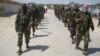 FILE - Members of the al-Shabab militant group patrol on foot on the outskirts of Mogadishu.