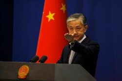FILE - Foreign Ministry spokesperson Wang Wenbin gestures for questions during the daily briefing in Beijing, July 23, 2020.