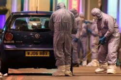 Police forensic officers work near a car at the scene after a stabbing incident in Streatham London, Feb. 2, 2020.
