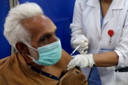 FILE - An elderly resident receives his first dose of the coronavirus disease vaccine, at a vaccination center in Karachi, Pakistan, March 10, 2021.