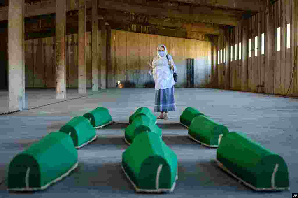 A woman prays next to coffins at the former U.N. base in Potocari, Bosnia. Nine newly found men and boys will be laid to rest when Bosnians commemorate 25 years since Srebrenica was overrun by Bosnian Serb forces, in Europe&#39;s worst post-WWII massacre.