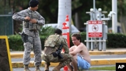 Security forces attend to an unidentified male outside the the main gate at Joint Base Pearl Harbor-Hickam, Dec. 4, 2019, in Hawaii, following a shooting.