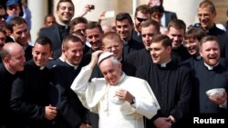 Pope Francis adjusts his skullcap as he poses with a group of priests during the weekly audience in Saint Peter's Square at the Vatican Sept. 28, 2016. The Pope's 2017 trip to Colombia will be his third to that country.