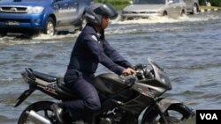 Seorang aparat di Thailand mengendarai sepeda motornya di tengah-tengah banjir yang masih merendam Bangkok, dekat Bandara Don Muang.