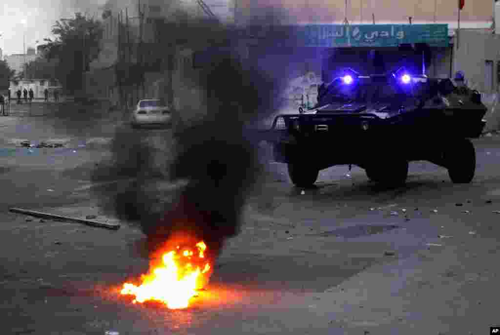An armored vehicle approaches the flames of a Molotov cocktail thrown by anti-government protesters, unseen, in Sanabis. (AP)