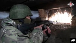 In this photo taken from video released by the Russian Defense Ministry on Oct. 24, 2024, a Russian soldier aims from a bunker in the Russian-Ukrainian border area in ​​the Kursk region, Russia. (Russian Defense Ministry Press Service photo via AP)