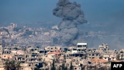 A smoke plume rises from explosions above destroyed buildings in the northern Gaza Strip on Jan. 13, 2025, in this picture taken from the Israeli side of the border.