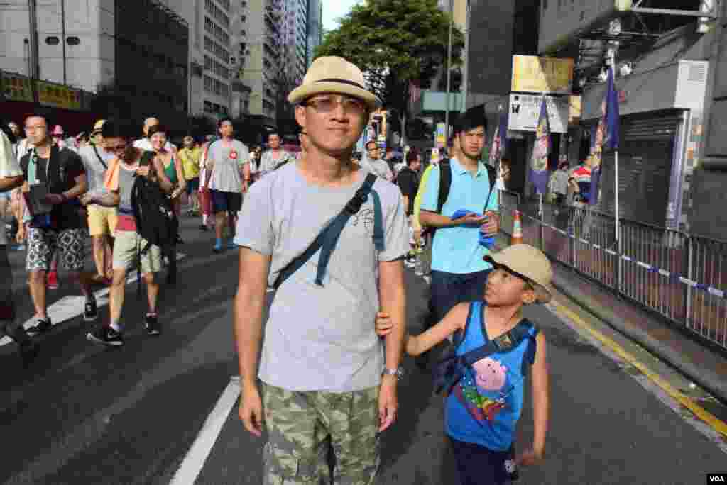 香港市民黃先生帶同9歲的兒子參加7-1大遊行，希望爭取真普選，他認為是漫長的道路。(美國之音湯惠芸拍攝)