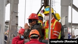 Rescue workers help a miner as he is brought to the surface at the Hushan gold mine after the January 10 explosion trapped workers underground, in Qixia, Shandong province, China January 24, 2021. 