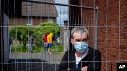 Julian, Romanian worker who stands behind the fence that was set up at the entrance of a housing of Romania slaughterhouse workers in Rosendahl, Germany, Tuesday, May 12, 2020.