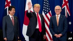 President Donald Trump, accompanied by Japanese Prime Minister Shinzo Abe, left, and Australian Prime Minister Malcolm Turnbull, right, waves to reporters at a meeting during the ASEAN Summit at the Sofitel Philippine Plaza, Monday, Nov. 13, 2017, in Mani