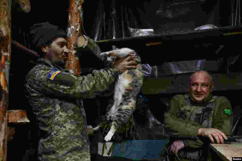 A serviceman of the 110th Territorial Defense Brigade of the Ukrainian Armed Forces holds a cat inside a dugout at a position on a frontline in Zaporizhzhia region, Ukraine, Jan. 21, 2025.