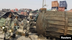 Soldiers of the People's Liberation Army's anti-chemical warfare corps, wearing gas masks, examine a container at the site of last week's explosions at Binhai new district in Tianjin, China, Aug. 16, 2015. 