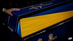 Rođak dodiruje kovčeg ukrajinskog vojnika Andrija Vorobjova na groblju Krivi Rih u istočnoj Ukrajini, ponedeljak, 24. aprila 2023. (AP Photo/Bernat Armangue)